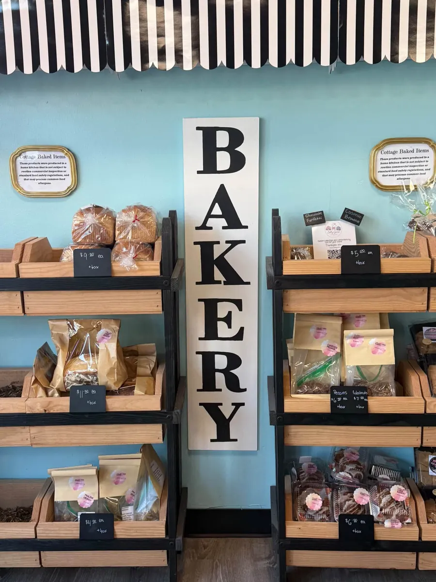 Bakery shelves of bagged breads and sweets from local makers beside a tall BAKERY sign