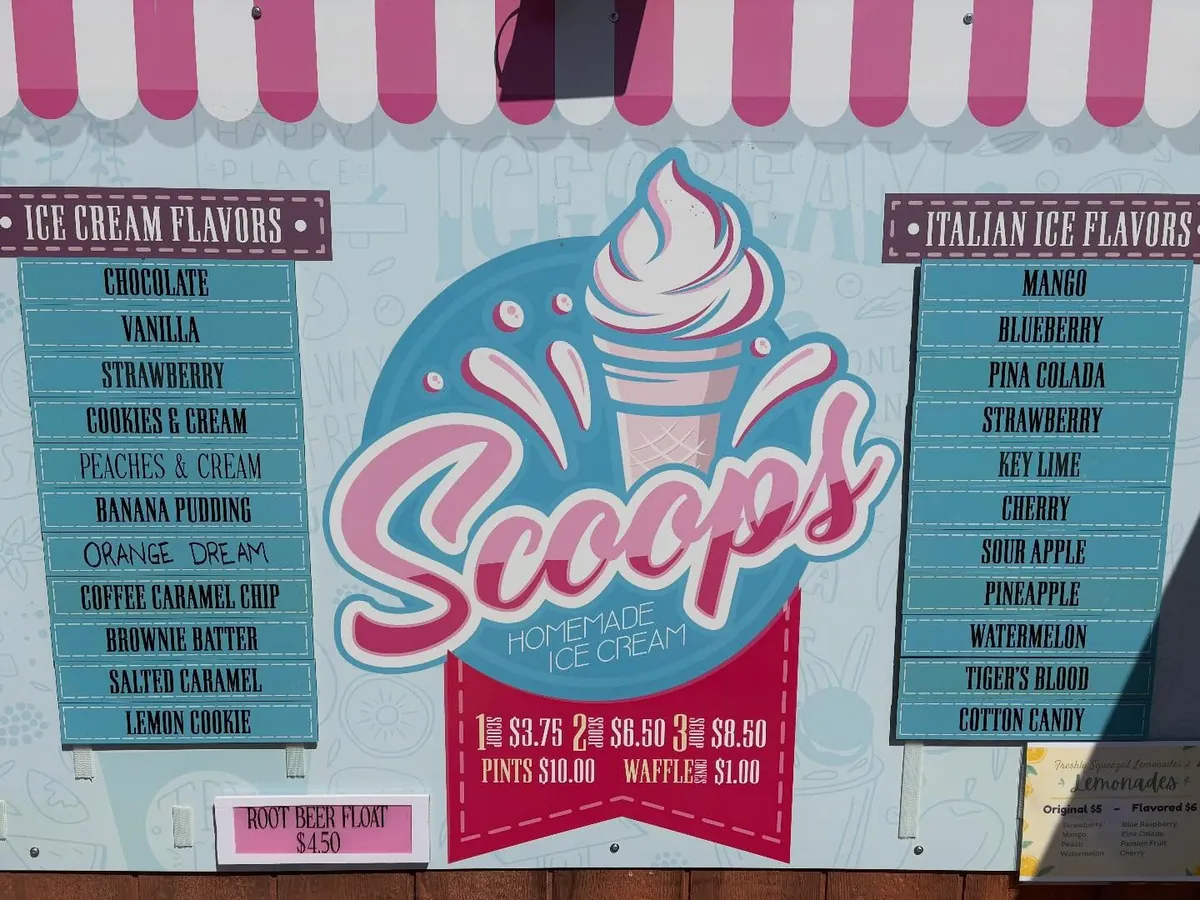 The park stand's menu board with ice cream and Italian ice flavors under a pink and white awning